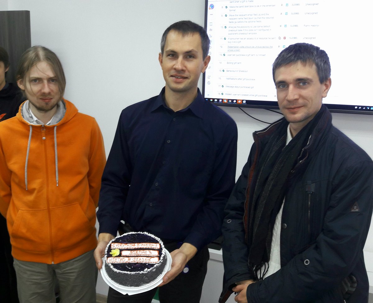 The author (in orange hoodie) and his colleagues with a cake.  Everything is fine on the cake written in 3 languages