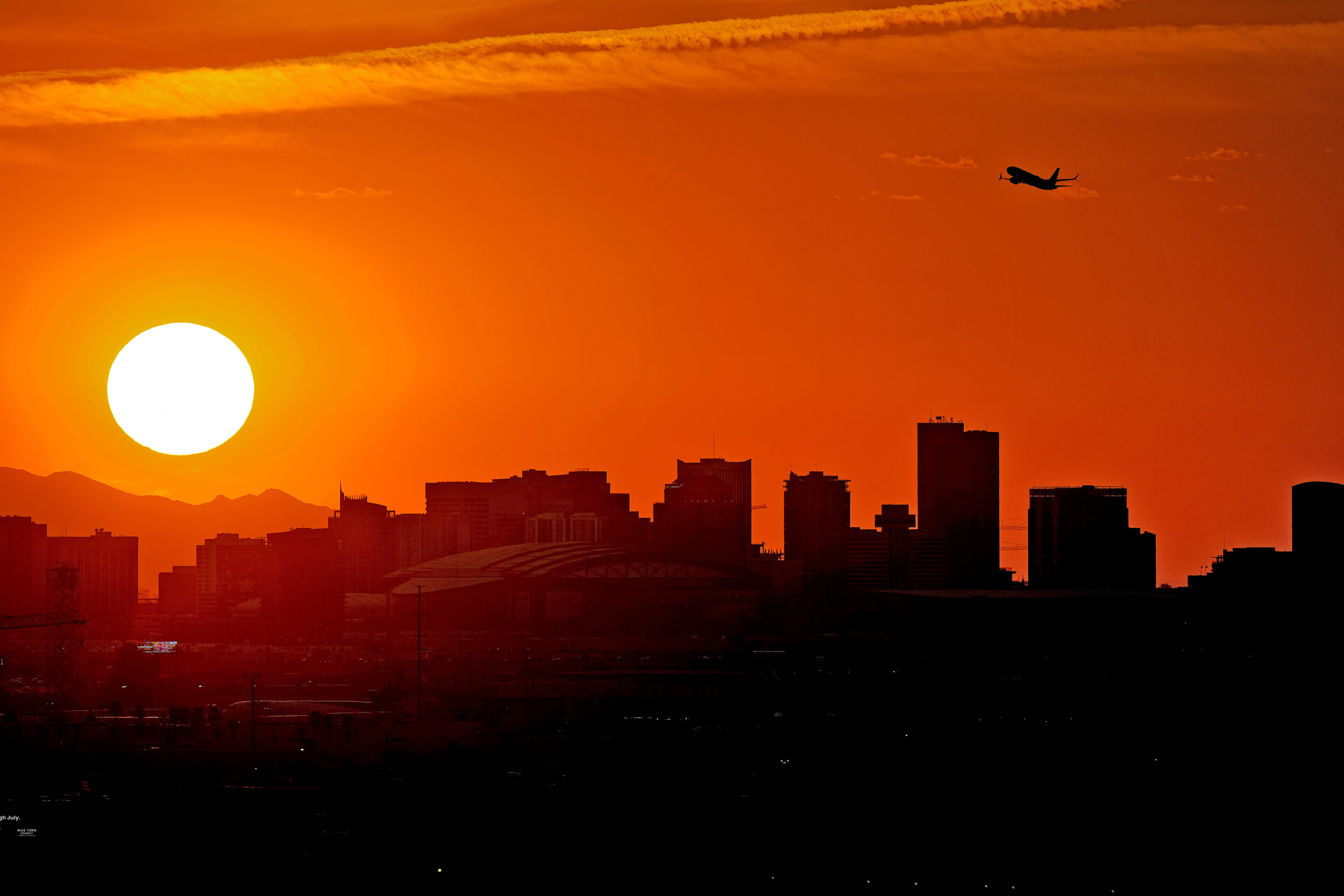 Самолёт вылетает из международного аэропорта Скай-Харбор на фоне захода солнца над Финиксом, 12 июля 2023 года. Бездомные - одни из тех, кто чаще всего погибает от экстремальной жары в метро Финикса.