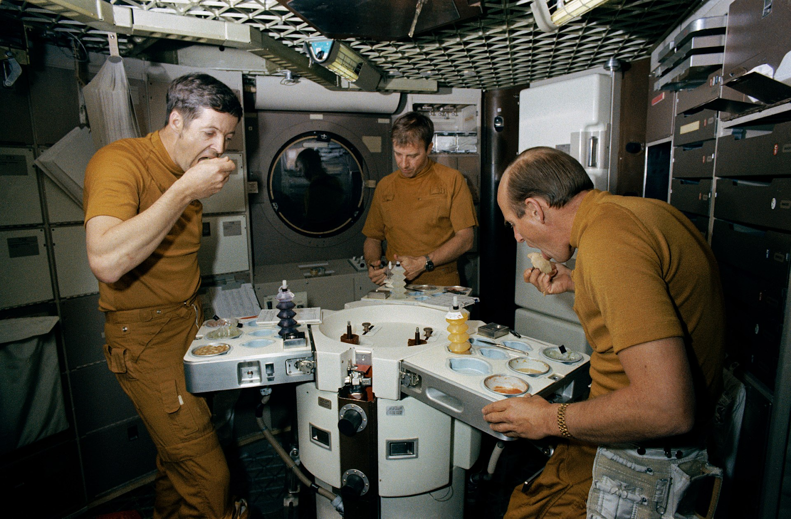 Астронавты употребляют пищу на «Скайлэбе»: специальный трехсторонний стол для экипажа из трех человек, печь для разогревания пищи, магнитные приспособления для столовых приборов и расширенное меню из 72 позиций (!!!)