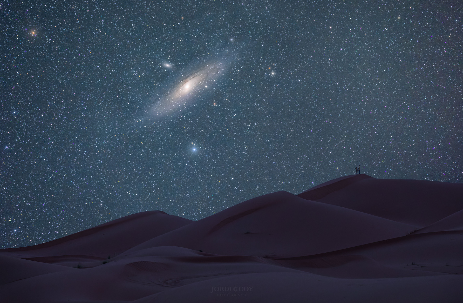 Галактики Андромеды заходит за барханы пустыни Сахара. Эта картинка не соответствует в точности видимости M31 из Южного полушария (ведь Сахара в северном). Но снимка этой галактики из Атакамы мне найти не удалось. Автор этого снимка Jordi Coy  