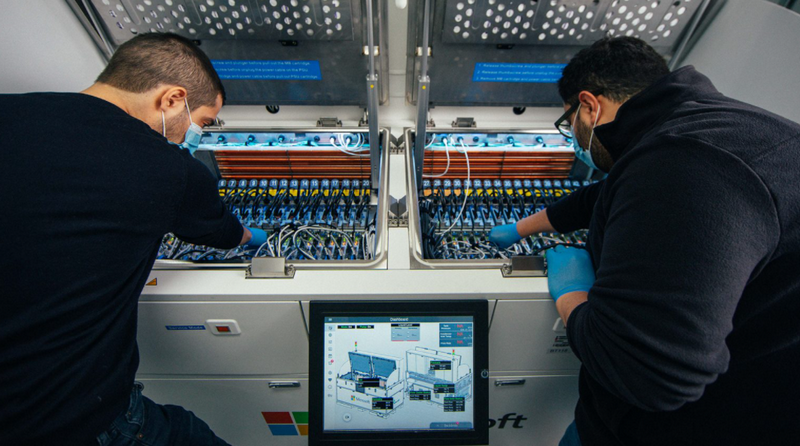 Иоаннис Манусакис, главный инженер-программист в Azure (слева), и Хусам Алисса, главный инженер по аппаратному обеспечению в группе Microsoft по расширенной разработке центров обработки данных (справа), осматривают внутреннюю часть резервуара двухфазного иммерсионного охлаждения
