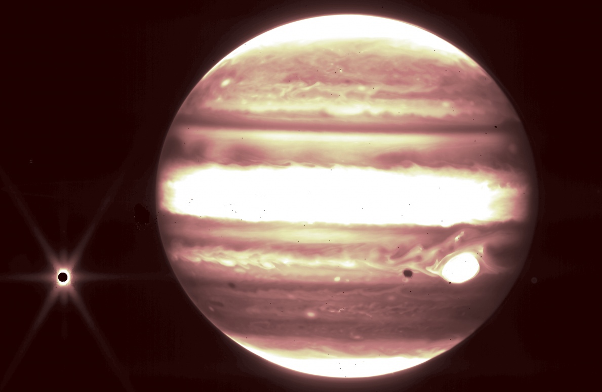 Юпитер (в центре) и его спутник Европа (слева) и ее тень (в районе большого красного пятна) видны через фильтр Джеймса Уэбба NIRCam 2,12 мкм
