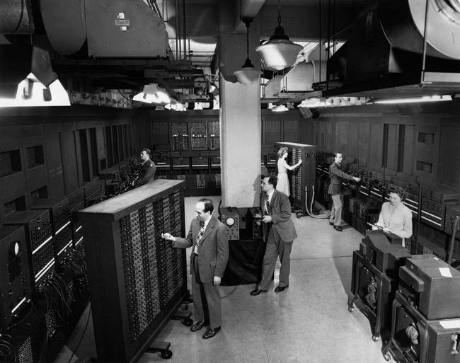 Дж. Преспер Эккерт (в центре слева) и Джон Мокли (у колонны) возле блока управления ENIAC
