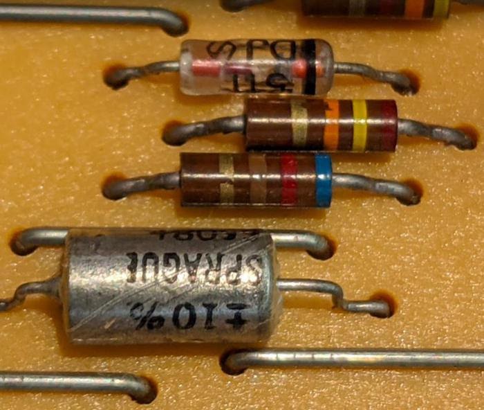 Диод (стеклянный цилиндр с полосками), резисторы (коричневые компоненты с полосками) и конденсатор (большой металлический цилиндр) создают задержку.