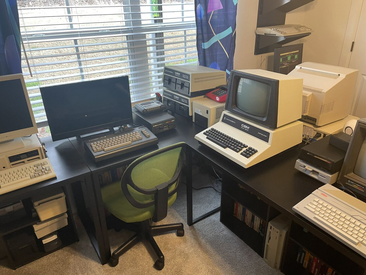 С этого ракурса мы видим Commodore CBM 8032, Commodore 16 и фрагмент IBM PCjr слева. Обратите внимание на винтажный красный телефон в стиле 1980-х годов.