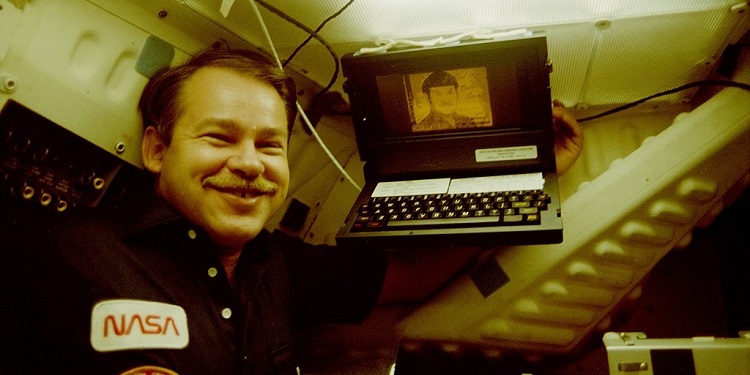 Астронавт О. Крейтон позирует на фоне портативного компьютера GRiD Compass на борту шаттла «Дискавери» 18 июня 1985 года. 