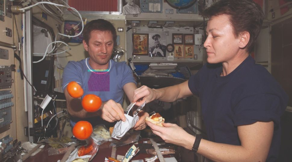 Космонавты Сергей Трещев и Пегги Уитсон готовят еду на МКС