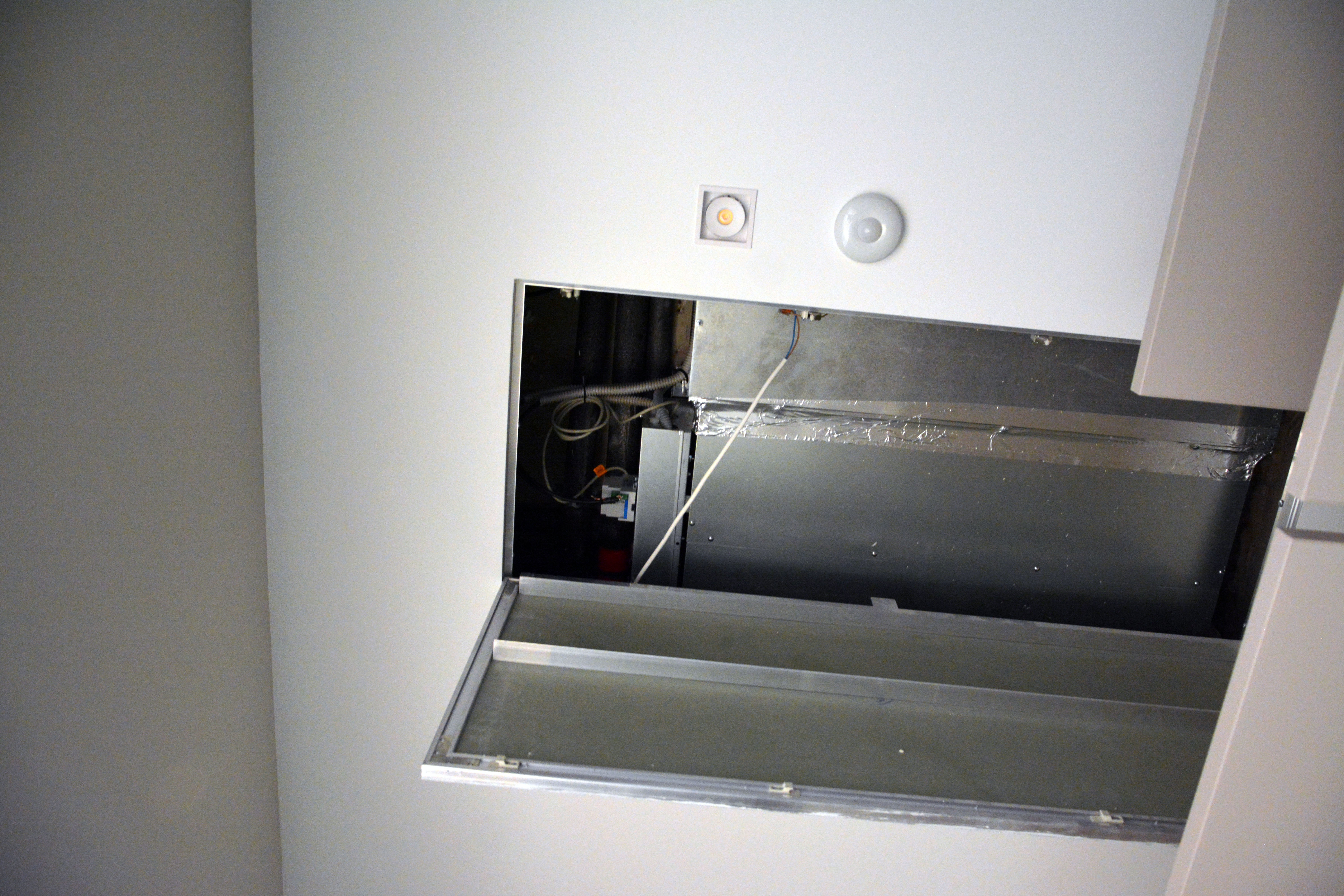 За дверцей в фальш-потолке расположился канальный кондиционер с модулем управления. На потолке можно заметить датчик движения