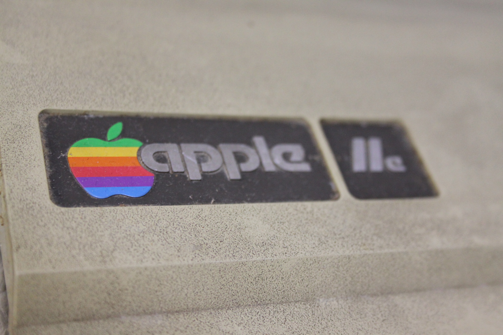 Фирменный значок Macintosh - цветное еще тогда яблочко. Модификация - Apple IIe. Отличается от оригинальной "двойки" кроме внешнего вида увеличенной оперативкой (Было 4/48КБ на выбор, стало 64 КБ), более дешевыми чипами ну и прочими не очень большими изменениями, для которых маркетологи решили не выпускать  новый Мак, а просто добавить буковку к названию)
