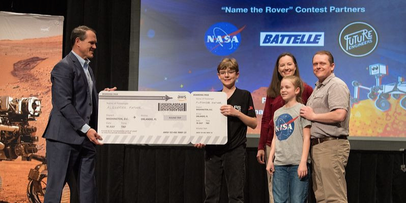 Представитель AWS Хайме Бейкер вручает царь-билет на мыс Канаверал победителю конкурса Name the Mars Rover 2020 Алексу Мэзеру и его семье. Фото: (НАСА / Обри Джеминьяни)