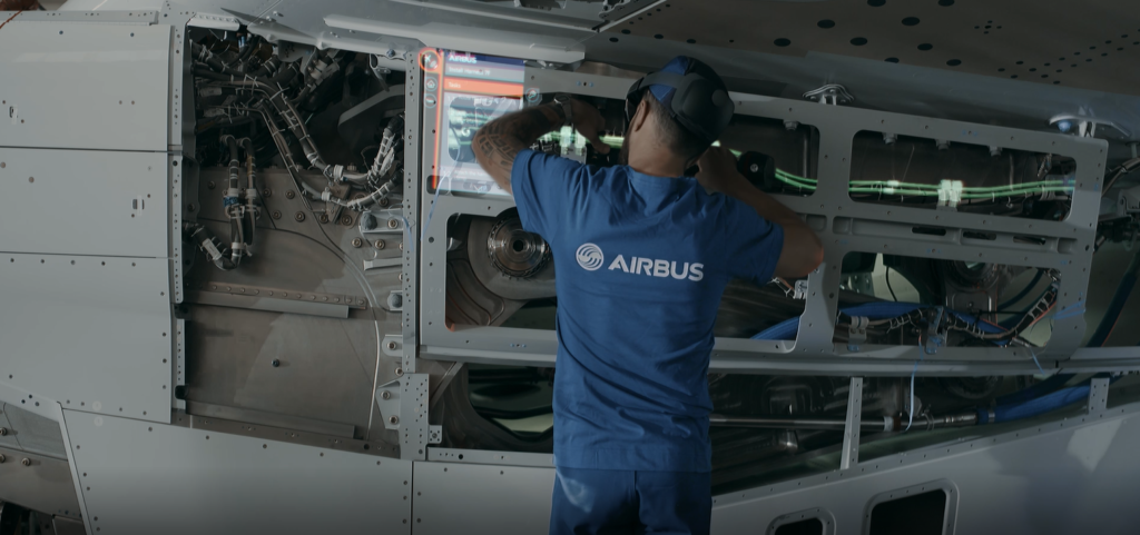 An Airbus engineers uses a HoloLens headset to perform maintenance on an aircraft.