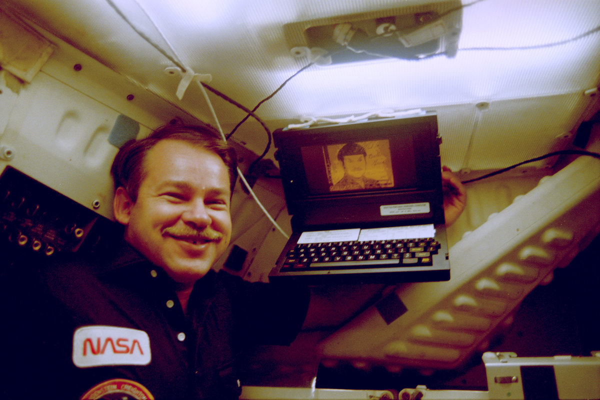 Astronaut John Creighton poses with onboard GRID computer