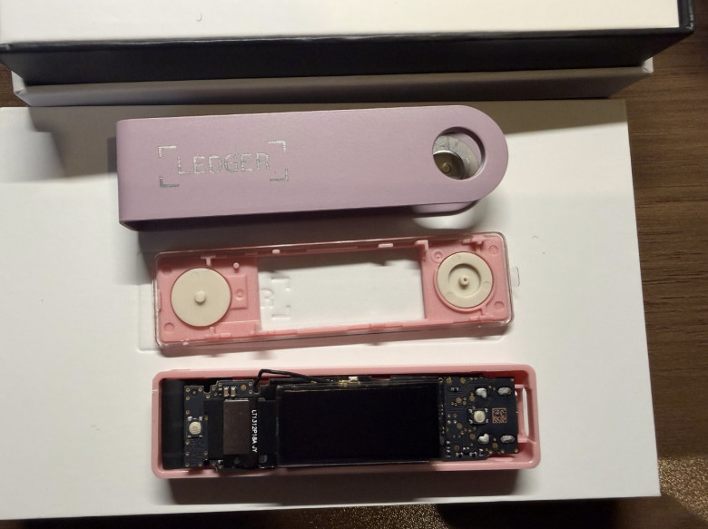Третий кошелёк Ledger Nano X, исследованный Марком Карпелесом. В этой закладке третьего поколения можно увидеть чёрную антенну, слегка выдающуюся сверху, вдоль края вскрытого корпуса, а также специально спроектированную гибкую печатную плату поверх платы кошелька; в этом случае ей сделали чёрное покрытие, чтобы она сливалась с оригинальной платой.