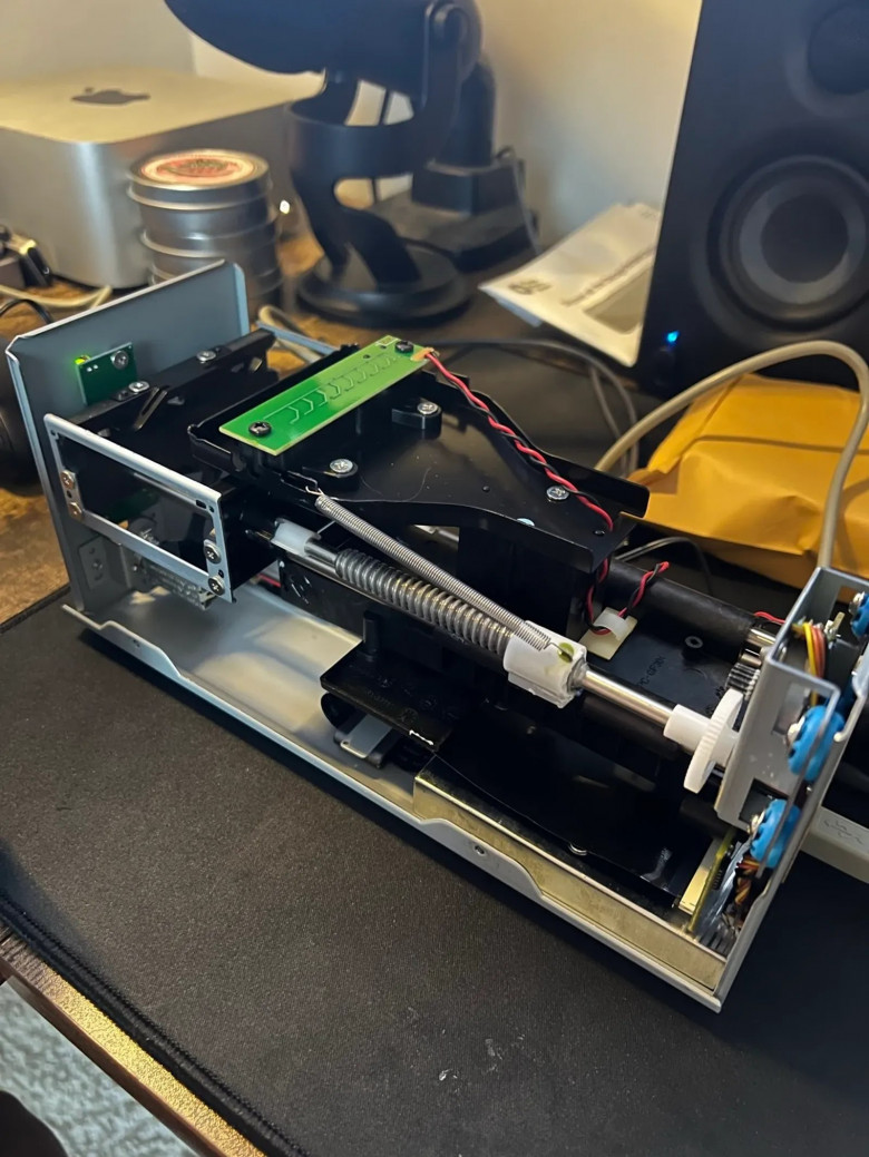 The Plustek scanner with its case removed, showing the carriage, a threaded rod, a spring and the motor gear.