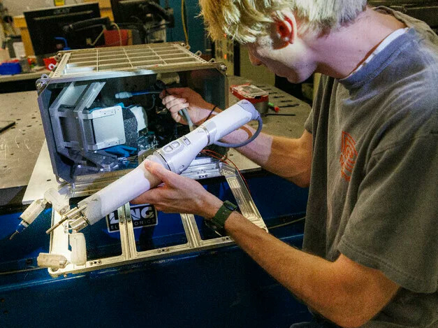 Шон Кримминс, выпускник инженерного факультета Университета Небраски, загружает роботизированную руку в кейс 11 августа перед испытанием на вибрацию.